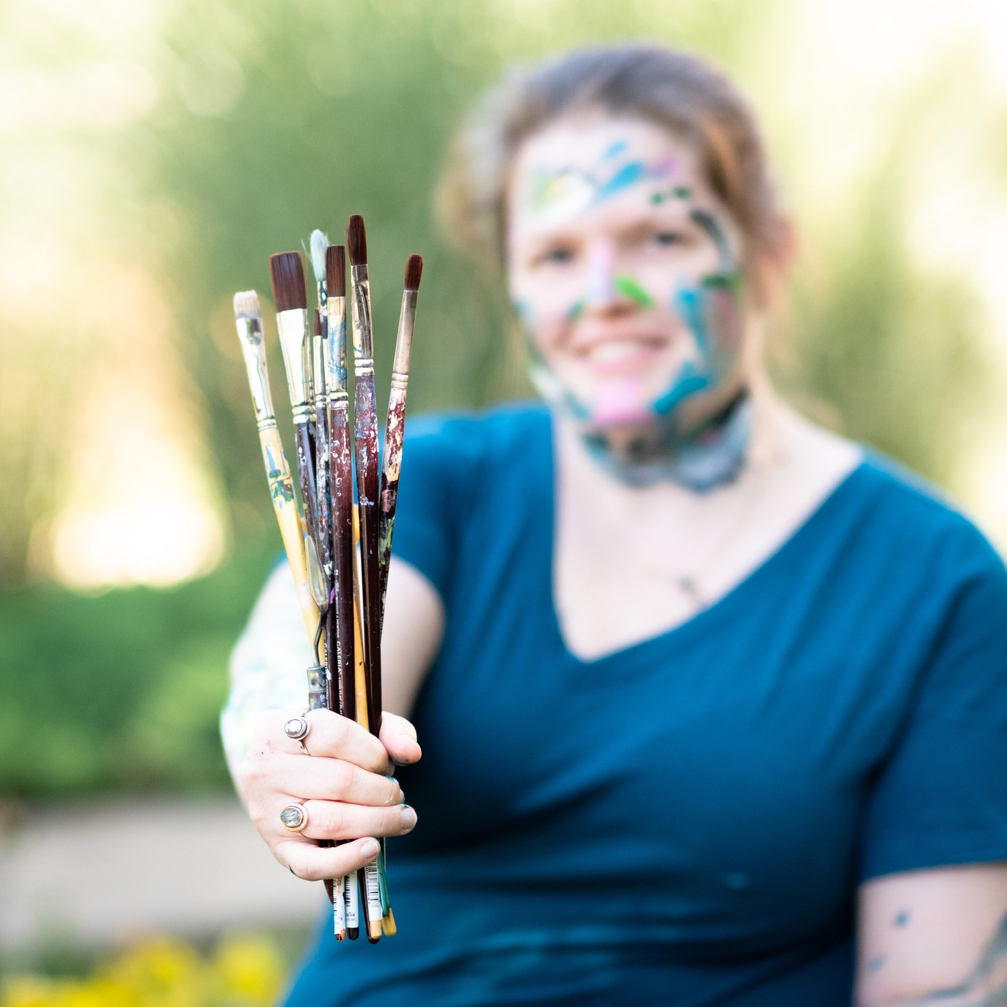 used paint brushes held by woman in blue t-shirt